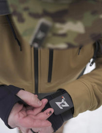 Black wrist band with white logo patch and red accent, worn on a hand