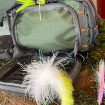 Gray waist pack with green front pocket and multicolor faux-fur keychain pouch