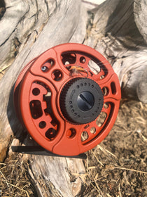 Fishing reel, matte fire orange with black center gear and round spool