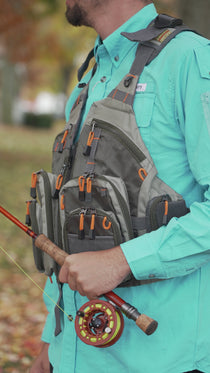 Gray mesh vest pack with multiple zip pockets, orange accents, adjustable chest straps