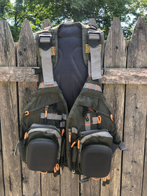 Olive utility vest with attached backpack, black mesh back, orange straps and pockets