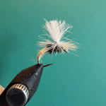 Fishing fly lure with white deer-hair body and brown hackle on barbed hook