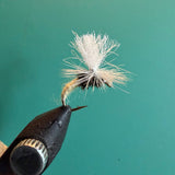Fishing fly lure with white deer-hair body and brown hackle on barbed hook