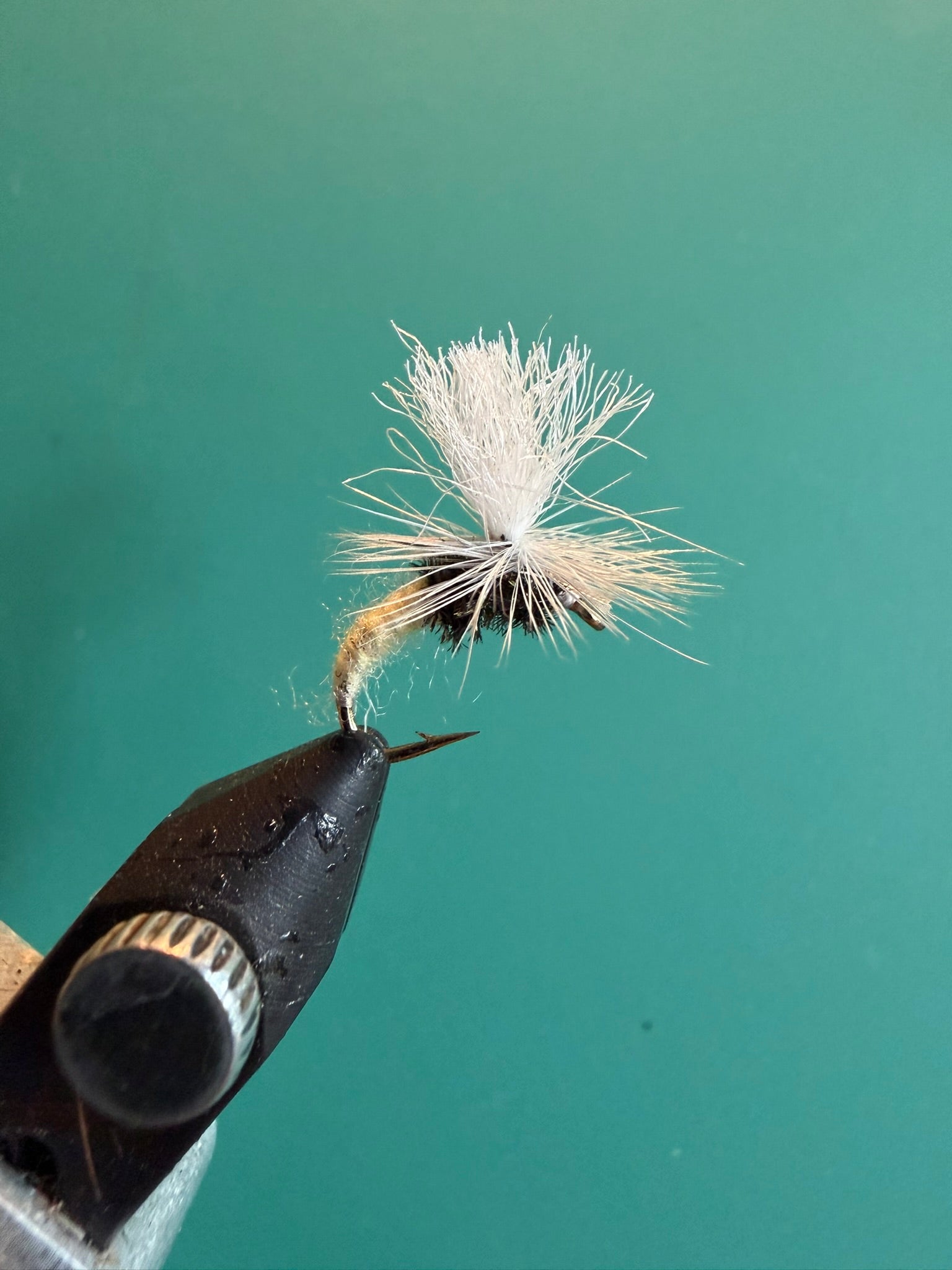 Fishing fly lure with white deer-hair body and brown hackle on barbed hook