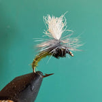 Fishing fly lure with white deer-hair body and dark thorax on barbed hook