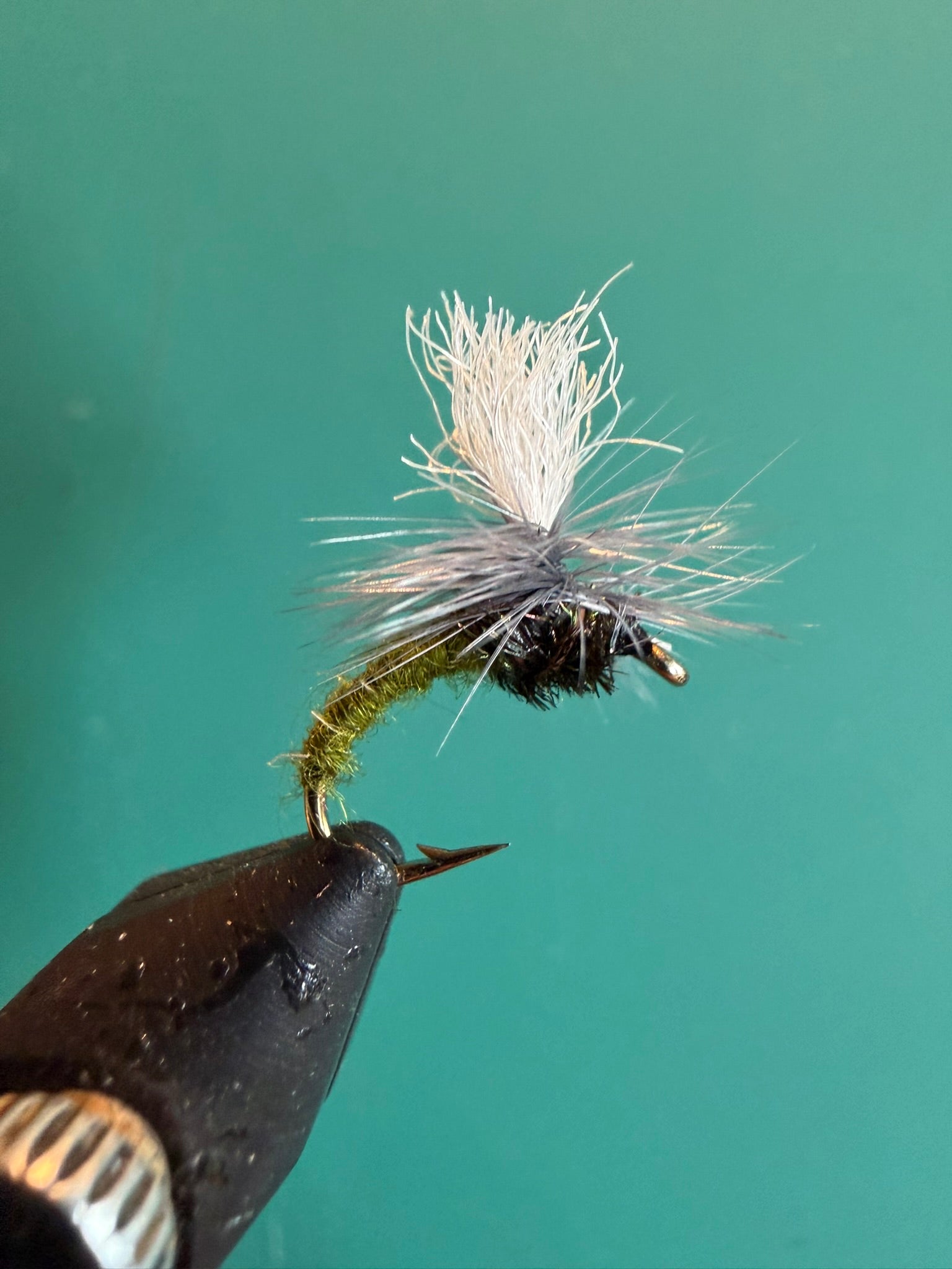 Fishing fly lure with white deer-hair body and dark thorax on barbed hook