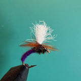 Fishing fly lure with white deer-hair body and purple tail on barbed hook