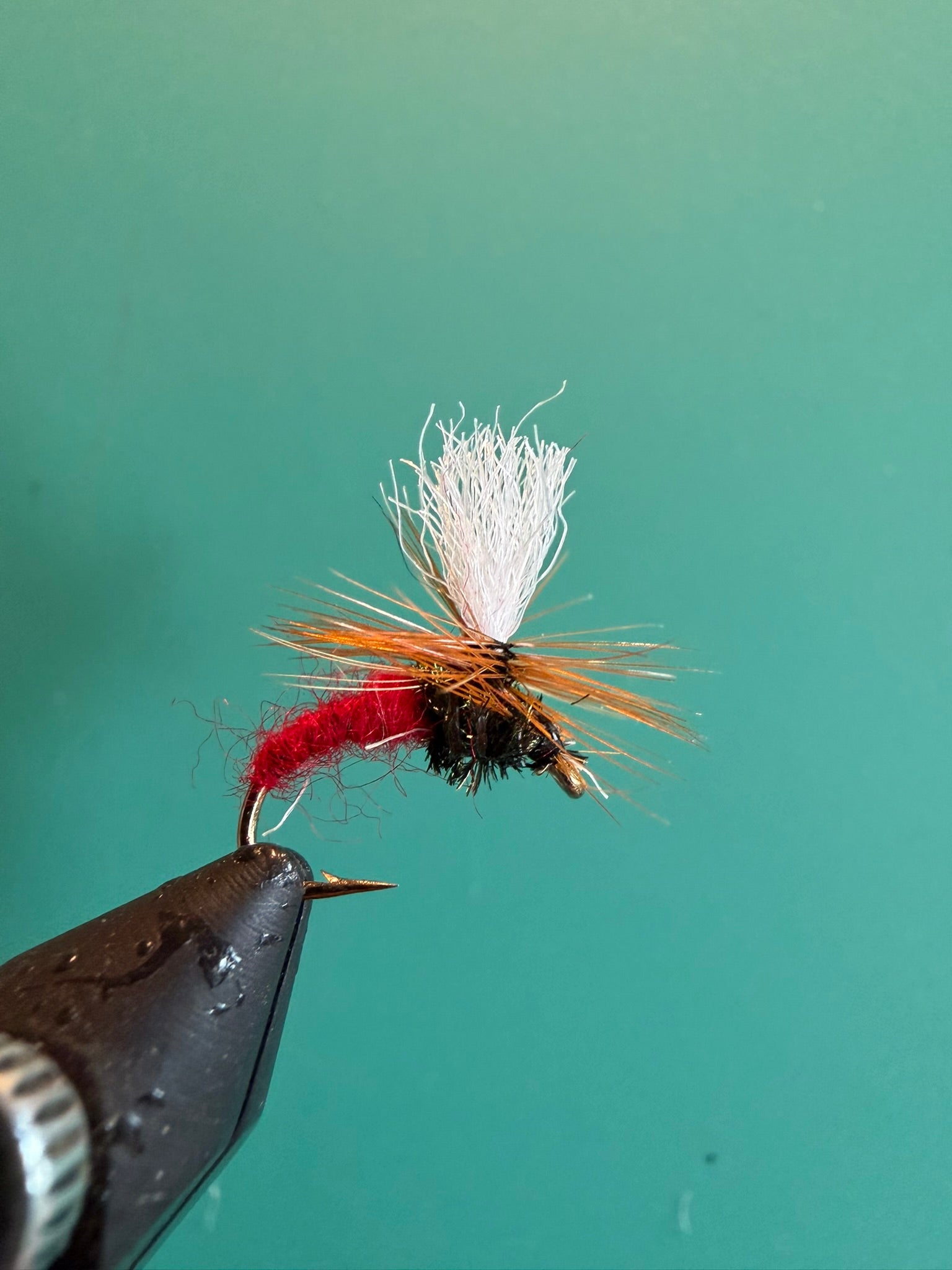 Fishing fly lure with white deer-hair body and red hackle on barbed hook