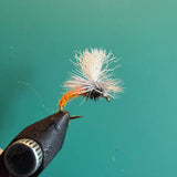 Fishing fly lure with white deer-hair body and orange hackle on barbed hook