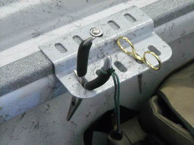 Metal side-mount tool rack bracket with oval holes, mounted on a bed rail