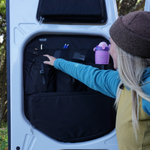 Black rear door storage organizer panel with shelves and pockets holding accessories