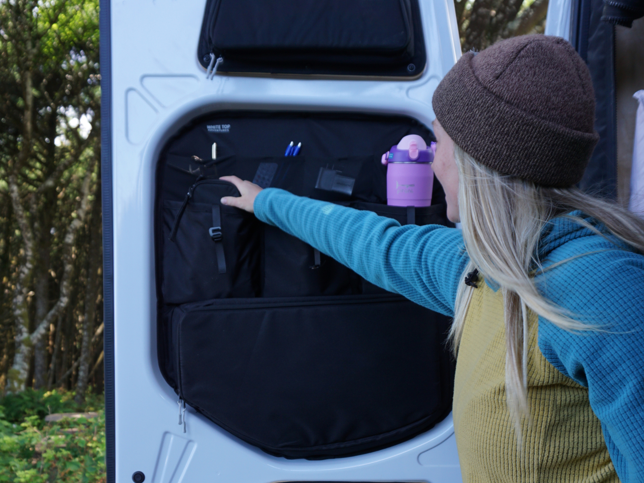 Black rear door storage organizer panel with shelves and pockets holding accessories
