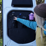 Black rear door storage organizer panel with shelves and pockets holding accessories