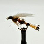 Wet fishing fly on a holder, with feathered tan and black body and red accent band