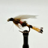 Wet fishing fly on a holder, with feathered tan and black body and red accent band