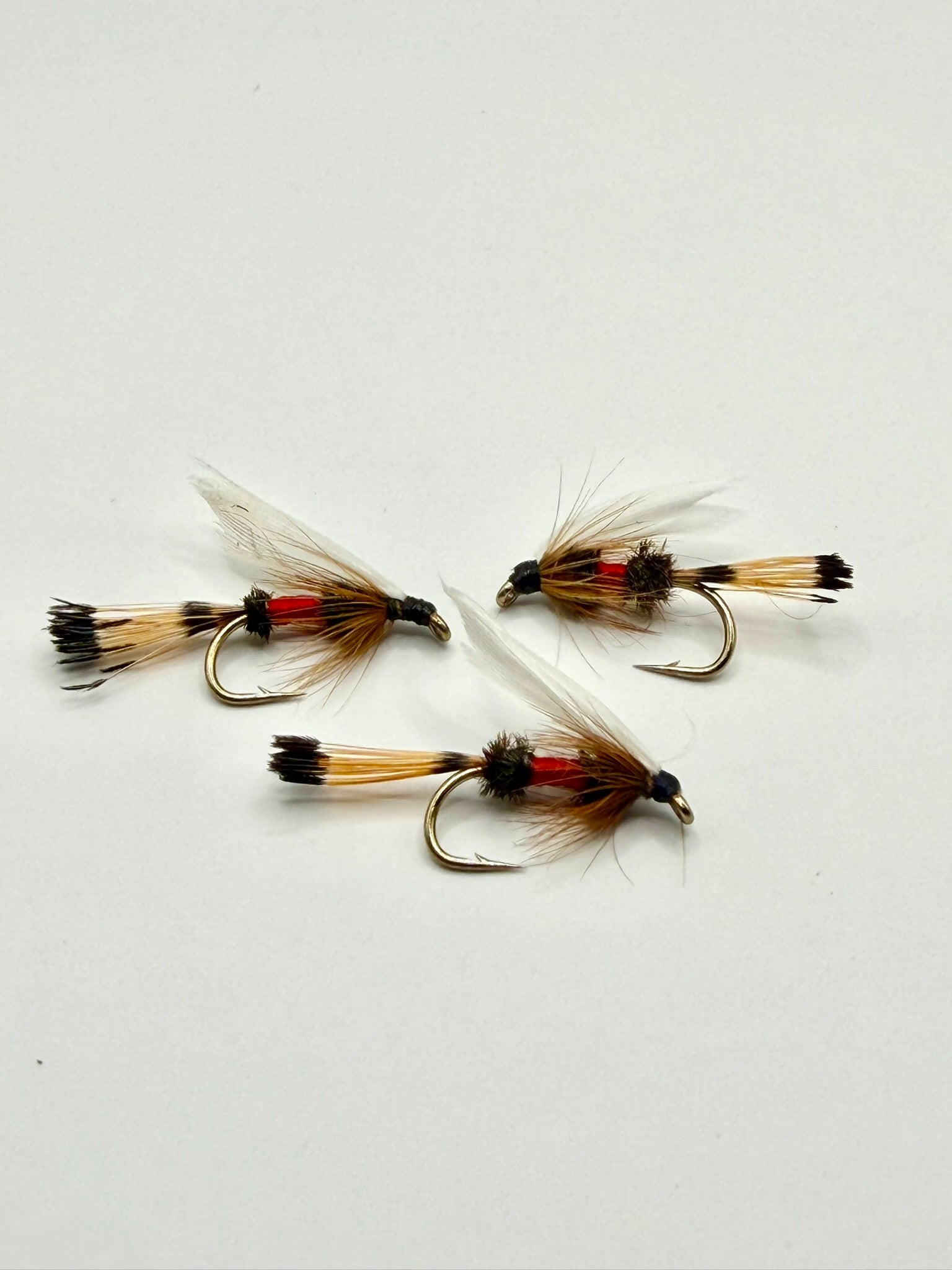 Set of three wet fishing flies with gold-brown bodies, red bands, and feathered wings