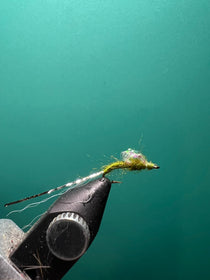 Olive sparkle fishing lure with silver body and trailing fibers on a hook