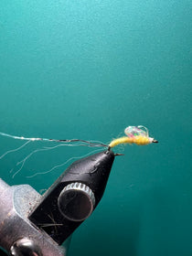 Black foam-bodied fishing fly with multicolor yarn tail and sparkle wing