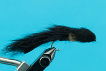 Black fishing fly lure with long fuzzy streamer on metal hook