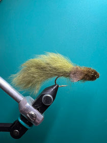 Olive sculpin-style fly lure with olive and yellow fur tail on a hook