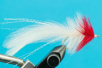 Fishing lure with white and red synthetic fly tail on a hook