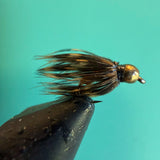 Soft hackle fishing fly with gold bead head and brown feather hackle on hook