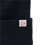 Black knit beanie with small rectangular patch and circular emblem on cuff