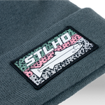 Dark teal knit beanie with ribbed cuff and stitched STLHD logo patch