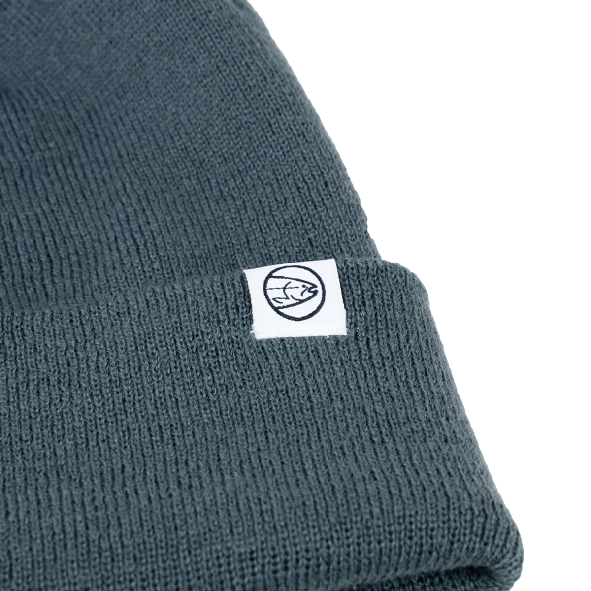 Dark teal knit beanie with ribbed cuff and small circular brand emblem patch