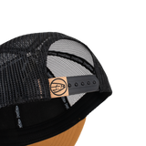 Black mesh trucker cap with snapback strap and tan leather logo patch