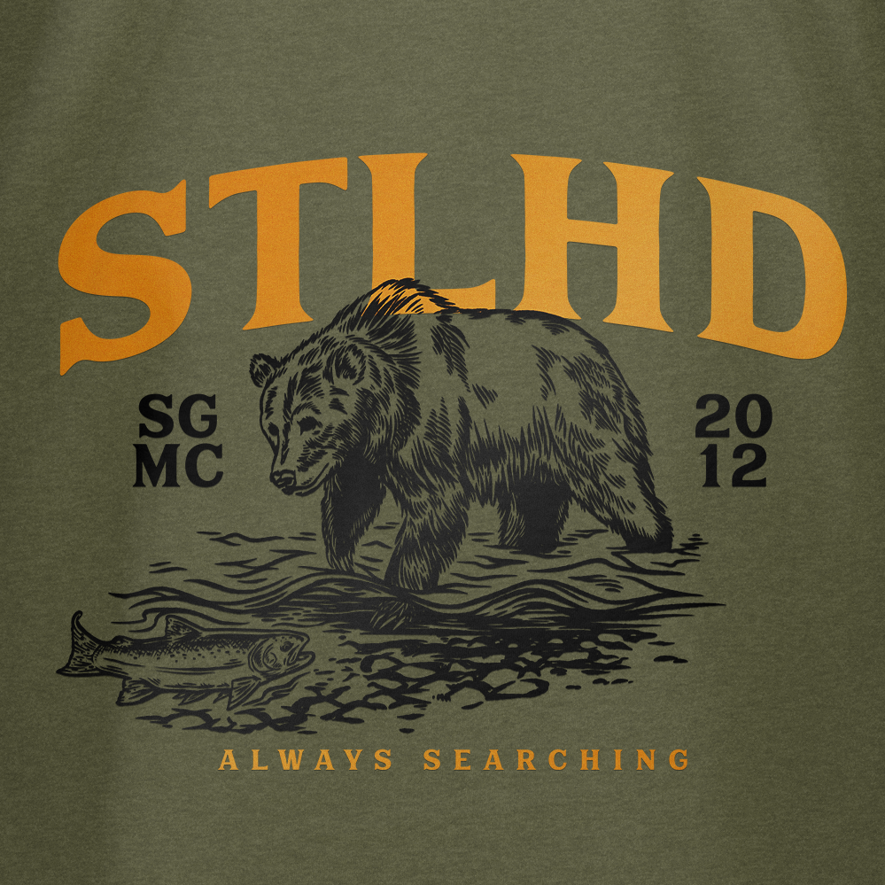 Green t-shirt close-up: STLHD letters over grizzly bear and 'ALWAYS SEARCHING'