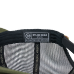 Olive green trucker cap interior with STLHD GEAR label and mesh lining
