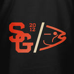 Black varsity T-shirt close-up: orange and cream chest logo graphic.