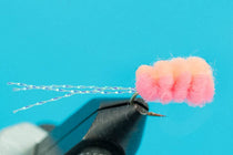 Black foam-bodied fishing fly with pink yarn dubbing tail and fiber strands