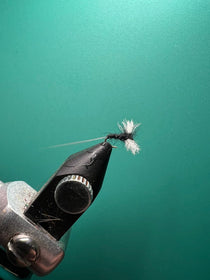 Black spinner fishing lure with metal body and feathered tail
