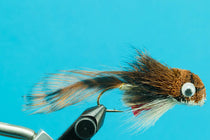 Brown sculpin fishing fly with white eye and feather tail