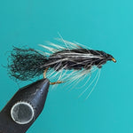Black and white woolly fishing fly with long flowing hackle tail