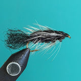 Black and white woolly fishing fly with long flowing hackle tail