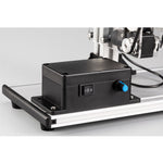 Black control box with on/off switch and blue button on machine base