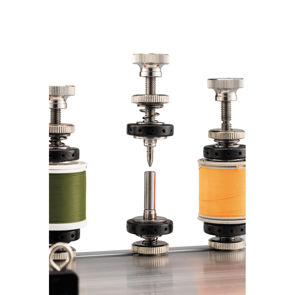 Spool holders with green and orange thread reels on machine