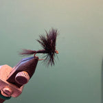 Wulff fly fishing lure with black fuzzy fibers and dark hook held in vise