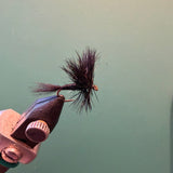 Wulff fly fishing lure with black fuzzy fibers and dark hook held in vise
