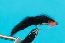 Fishing streamer fly with black fur wing and ribbed body on hook